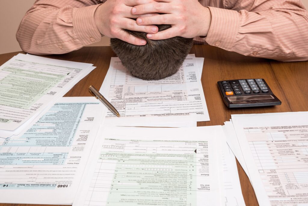 A man with his head down in front of numerous tax forms after receiving a tax audit notification and deciding it is time to call a Mississippi tax audit attorney.