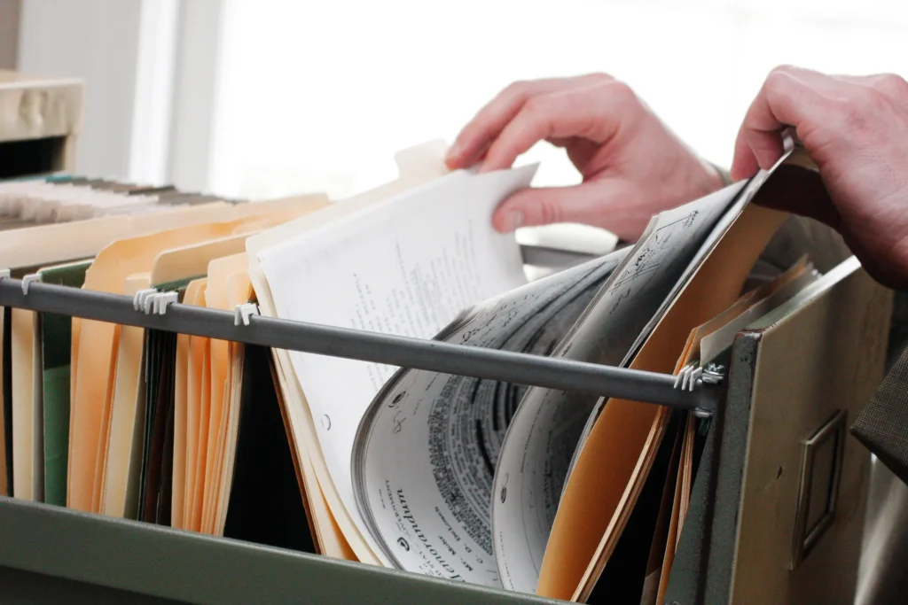 A person going through a filing cabinet and looking at paperwork.